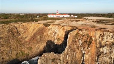 Gün batımında tepedeki Cabo Sardao deniz fenerinin manzarası. Alentejo Sahili, Portekiz