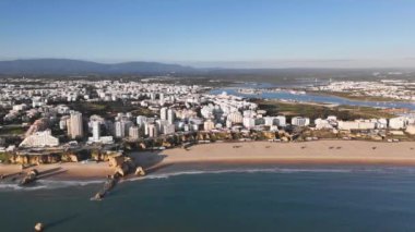 Portekiz 'deki Portimao tatil köyünün geniş panoramik manzarası. Kışın alçak mevsimde kocaman boş bir plaj ve arka planda deniz kenarındaki evler.