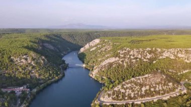 Krka Ulusal Parkı 'nın üzerinde, Skradinski şelalesine doğru uçan bir uçak. Tekne nehirde yelken açar.