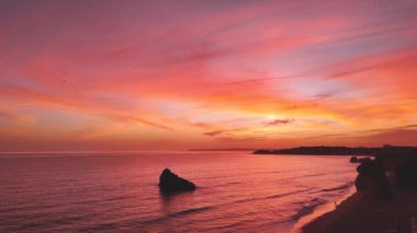 Sahilde ve okyanusta canlı renkli bulutlar. Portekiz, Portimao 'da gün batımı