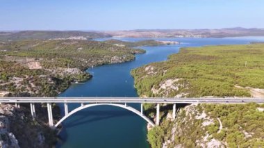 Hırvatistan 'ın Dalmaçya bölgesindeki Krka nehri üzerindeki kemer köprüsünün panoramik manzarası. Prokljan Gölü Prokljansko Jezero arka planda