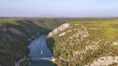 Hırvatistan 'ın Krka Ulusal Parkı' ndaki kanyondaki köprünün altından yolcu gemisi kalkıyor. Kuş bakışı