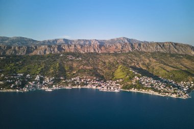 Dağ sırasının eteğindeki küçük köylerle Adriyatik Denizi kıyı şeridinin hava manzarası. Bölünmüş Dalmaçya bölgesi, Hırvatistan