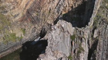 Dik kayanın tepesindeki yuvada oturan beyaz Avrupalı leyleğin havadan görünüşü. Cabo Sardao, Portekiz 