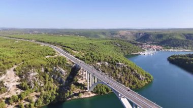 Nehir boyunca uzanan kemer köprüsünün hava panoramik görüntüsü ve arka planda Skradin kasabası. Krka Ulusal Parkı, Hırvatistan