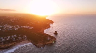 Portekiz 'de Algarve sahilinin yukarısında gün doğumu. Fenerli pelerin Farol da Ponta do Altar ön planda. 