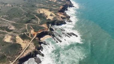 Portekiz 'in popüler yürüyüş alanı olan Rota Vicentina boyunca dik kayalar ve dev sörf yapan kıyı şeridinin yukarıdan aşağı hava manzarası.