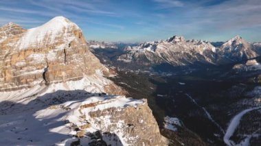 Dolomitlerde beyaz bulutlar olan açık mavi gökyüzünün altındaki karla kaplı bir dağ sırasının havadan görünüşü.
