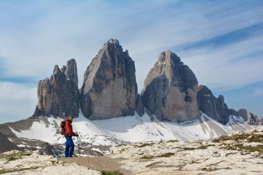 Güneşli bahar günlerinde Dolomite Alplerinde Tre Cime di Lavaredo dağının önünde sırt çantalı bir yürüyüşçü duruyor.
