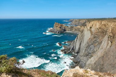 Arrifana 'daki Atlantik Okyanusu' nun üzerindeki sarp ve sarp kayalıklar. Baharda Portekiz kıyılarının güçlü güzelliği