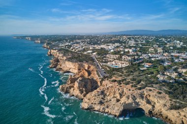 Carvoeiro ve Lagoa 'nın yüksek uçurumları ve kayalıklarda tahta tahta kaldırımları olan turistik kasabaların havadan panoramik manzarası. Algarve, Portekiz