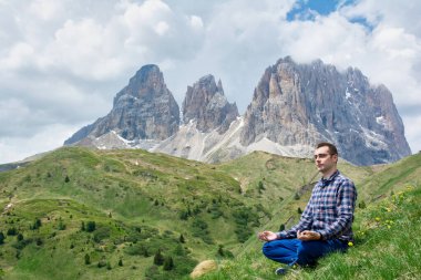 İnsanoğlu doğada huzur içinde meditasyon yapar yemyeşil bir yamaçta arkasında muhteşem Dolomite Dağları ile