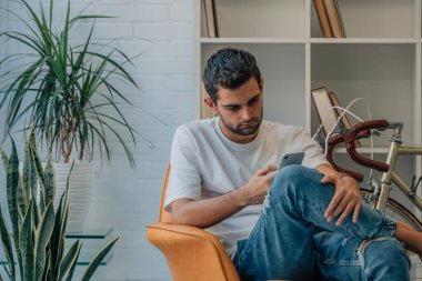 Genç adam cep telefonuyla evde.