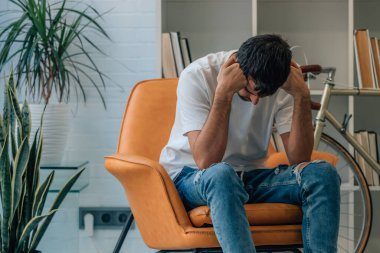 Evde yalnızlık içinde depresyonda olan genç bir adam.
