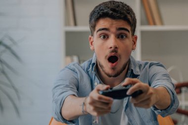 Evde joystick çalan genç bir adam var.