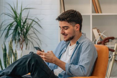 Evde cep telefonu olan genç bir adam ya da öğrenci