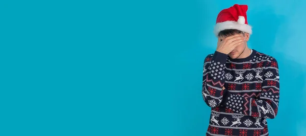 一个孤独的年轻人 身穿圣诞毛衣 头戴圣诞帽 满脸愁容 — 图库照片