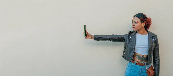 Черная Латинская Девочка Смотрит Мобильный Телефон Протянутой Рукой Фоновой Стеной — стоковое фото