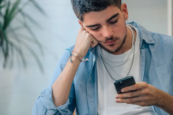Ung Man Hemma Tittar Mobiltelefon Uttråkad — Stockfoto