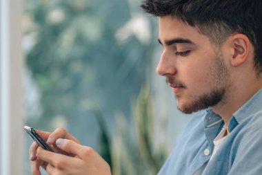 Evde cep telefonu olan genç bir adam ya da öğrenci