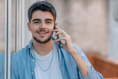 Bin yıllık genç adam sokakta cep telefonuyla konuşuyor.