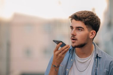 Sokaktaki genç adam sesi kaydediyor ya da cep ya da cep telefonuyla sesli mesaj gönderiyor