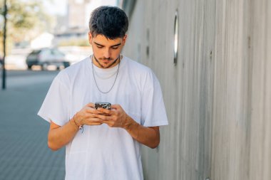 Sokaktaki genç adam telefona ya da akıllı telefona bakıyor.