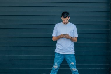 Cep telefonu olan genç adam elinde fotokopi aletiyle caddede duruyor.