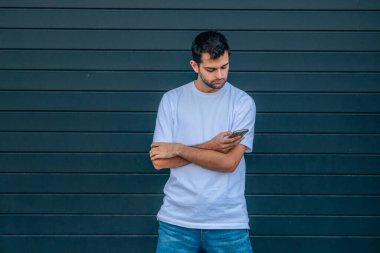 Sokaktaki genç adam cep telefonuna bakıyor.