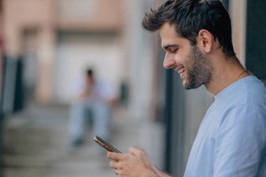 Sokaktaki genç adam cep telefonuna bakıyor.