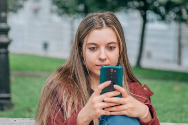 young man or student in the park with mobile phone
