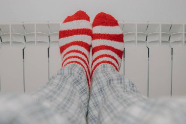 Çizgili çoraplı ayaklar evdeki ısıtma radyatöründe.