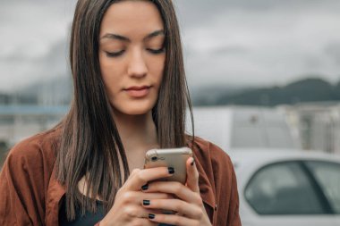 Sonbaharda sokakta cep telefonuna bakan bir kız.