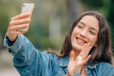 Cep telefonlu bir kadın sokakta selfie çekiyor.