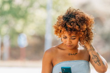 Latin kız cep telefonuna bakıyor.