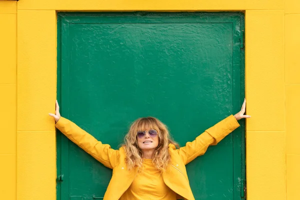 Szczęśliwy Średnim Wieku Kobieta Zielone Drzwi Żółtą Ścianą — Zdjęcie stockowe