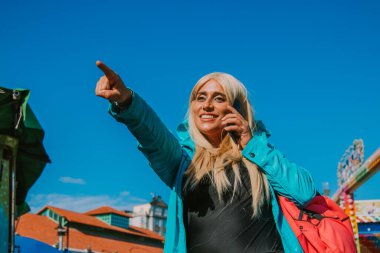 Kadın cep telefonuyla dışarıyı işaret ediyor