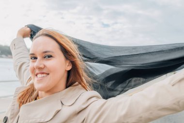 Açık havada uçan atkısı olan gülümseyen kadın.