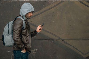 Sonbaharda veya kışın sokakta cep telefonuyla yürüyen bir adam.