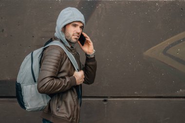 Sırt çantalı bir adam cep telefonuyla konuşuyor.