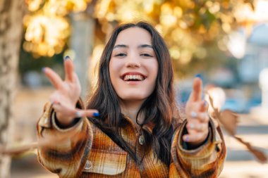 Sokaklarda sonbahar yapraklarıyla gezen genç bir kızın portresi.