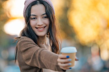 Sonbaharda genç bir kadın bir fincan kahveyle dışarıda.