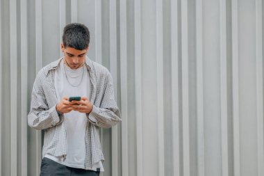 Sokakta cep telefonuyla duran genç adam.