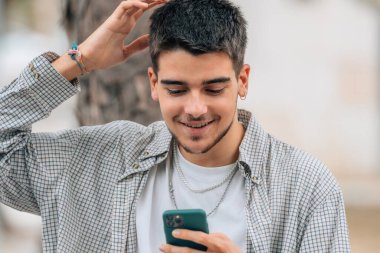 Cep telefonlu genç adam gülümsüyor.