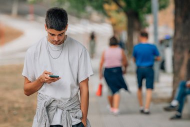 Sokaktaki genç adam cep telefonuna bakıyor.