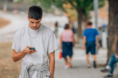 Sokaktaki genç adam cep telefonuna bakıyor.