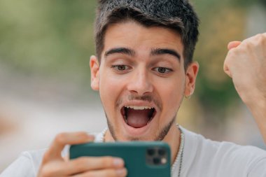 Heyecanlı genç adam oynuyor ya da cep telefonuna bakıyor.