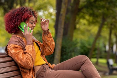 Cep telefonlu bir kız bankta oturuyor.