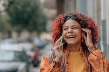 Modern kadın sokakta cep telefonuyla konuşuyor.