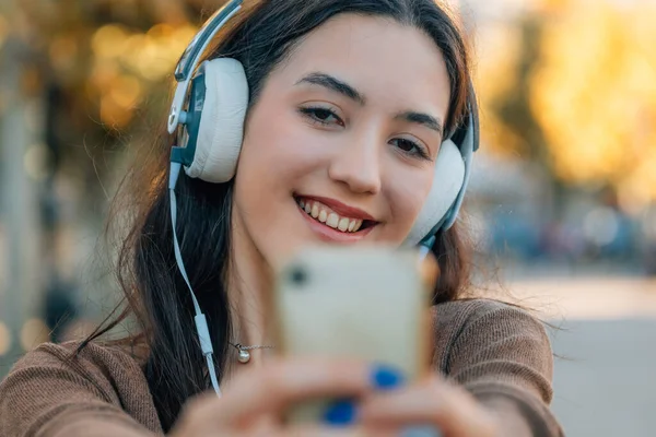 girl in the street with mobile phone and headphones taking photos or selfie
